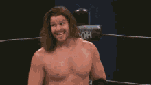 a shirtless wrestler in a ring with a r on the corner