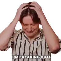 a man in a striped shirt has his hands on his head and the words i 'm freaking out above him