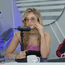 a woman wearing sunglasses is sitting in front of a microphone in a studio .
