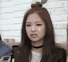 a woman with long hair is making a funny face while wearing a choker and a bun .
