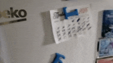 a beko brand refrigerator with a calendar hanging on the door