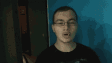 a young man wearing glasses and a black shirt looks at the camera