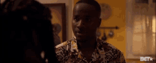 a man in a camouflage shirt is talking to a woman in a room .