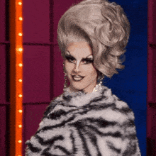a drag queen is wearing a zebra print coat