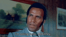 a man in a suit and tie is talking to another man .