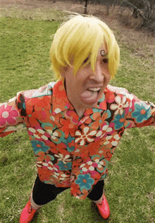 a man wearing a yellow wig and a floral shirt is standing in the grass