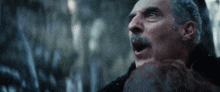 a man with a mustache and gray hair is screaming in the woods