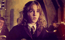 a girl with long curly hair is wearing a harry potter uniform