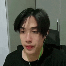 a young man is wearing headphones and making a funny face while sitting in a chair .
