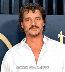 a man with curly hair and a beard is wearing a white shirt and says good morning .