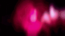 a close up of a pink glowing object with a black background