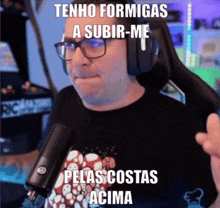 a man wearing glasses and headphones stands in front of a microphone and says tenho formigas