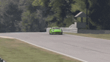 a green sports car is driving on a track