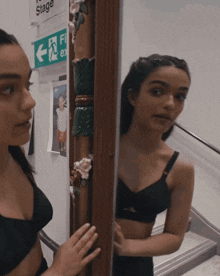 a woman looks at her reflection in a mirror in front of a stage sign
