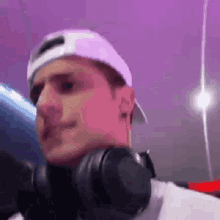 a man wearing headphones and a white hat is smiling .