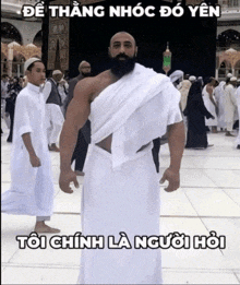 a man with a beard is standing in front of a crowd of people with a caption in foreign language