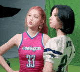 a girl in a washington jersey is standing next to another girl in a football jersey
