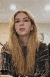 a woman with long blonde hair is wearing a black and white striped shirt