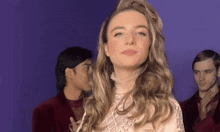 a woman with long blonde hair is standing in front of a group of men