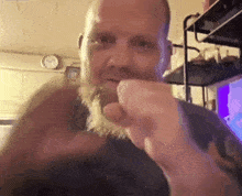 a man with a beard is making a fist in a room .