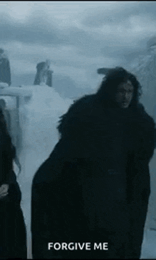 a man in a black coat is standing in the snow with the words `` forgive me '' above him .