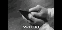 a black and white photo of a person holding a cell phone in their hands .