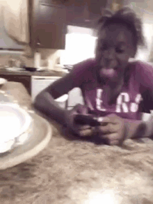 a girl is sitting at a table looking at her phone