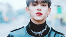a young man wearing a black turtleneck and a necklace