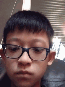 a close up of a person wearing glasses with a serious look on their face