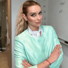 a woman in a light blue jacket stands with her arms crossed in front of a white board that says ucsd2