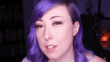a close up of a woman 's face with purple hair .