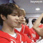 a group of people wearing red jerseys with the word heysaym on the bottom right