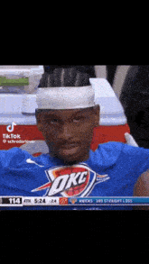 a basketball player wearing a headband and a blue shirt with okc on it