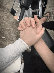 a person holding another person 's hand while sitting on a scooter