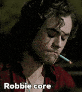 a close up of a man smoking a cigarette with the words robbie core above him .