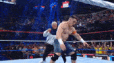 a man without a shirt is dancing in a wrestling ring while a crowd watches .