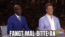 a man in a blue suit and tie is sitting next to another man in a blue suit .