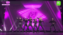a group of women are standing on a stage with purple lights behind them .