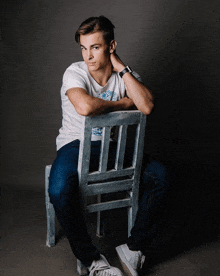 a young man is sitting on a chair with his hand on his head