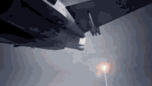 a fighter jet is flying through a cloudy sky with a light in the background .
