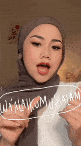 a woman wearing a hijab and a white shirt says wa alaikumussalam
