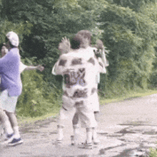 a group of people are walking down a road and one of them is wearing a shirt that says ' roxy ' on it