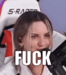 a woman is sitting in a chair holding a microphone and making a face with the word fuck .