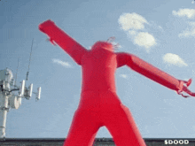 a red inflatable man is standing in front of a building that says $ dood on it