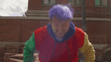 a man with purple hair wearing a colorful sweatshirt