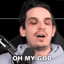 a man in front of a microphone with his eyes closed says " oh my god "