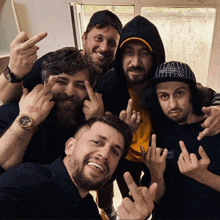 a group of men are posing for a picture and one of them has a tattoo on his wrist that says " may "