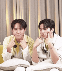 two young men are making funny faces while sitting on a couch