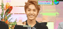 a young man is smiling in front of a sign that says mblaq on it