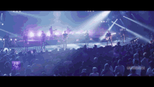 a group of people playing instruments on a stage in front of a crowd with the words " let 's go " on the bottom right